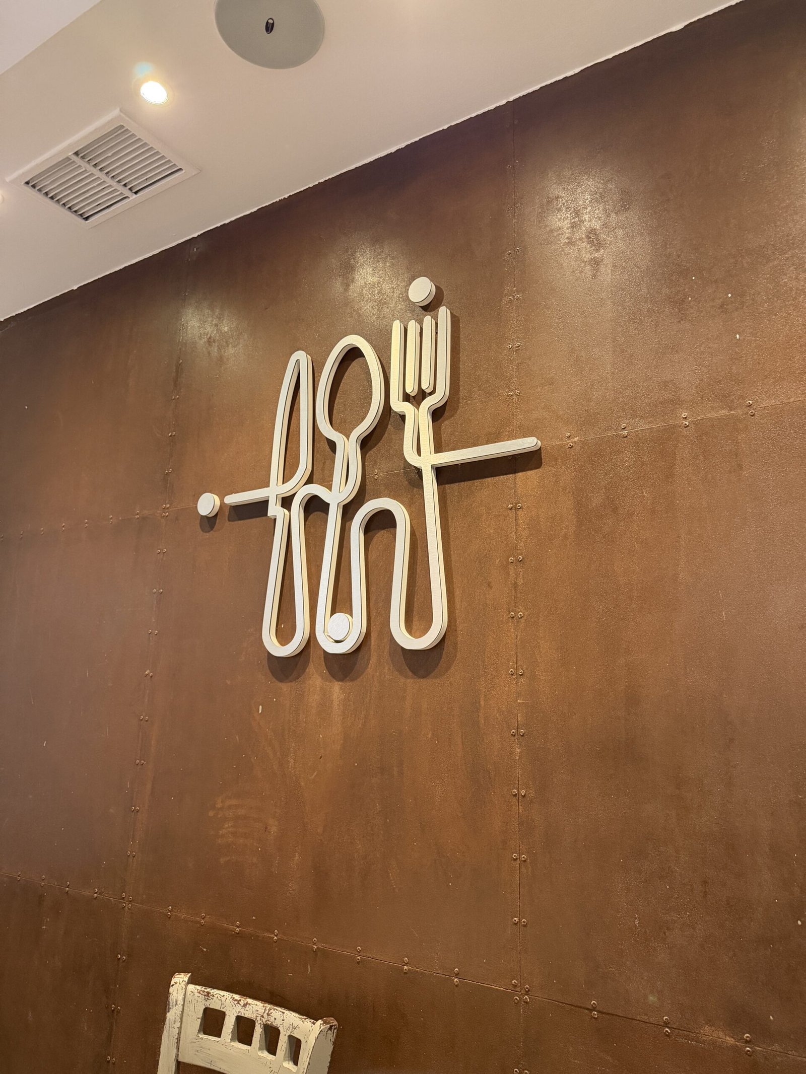 Logo en forme de couverts sur le mur couleur rouille du restaurant Albor à Madrid